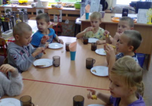 Dzieci podczas podwieczorku zajadają ciasto.